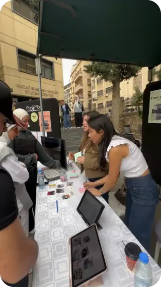 The DeTOKs booth in action: students at the table filling in surveys on tablets.